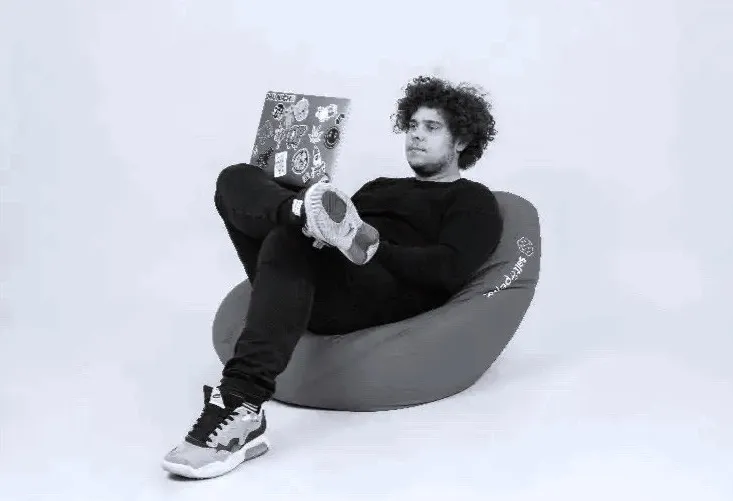 A colleague working on a laptop from a Salt & Pepper beanbag.