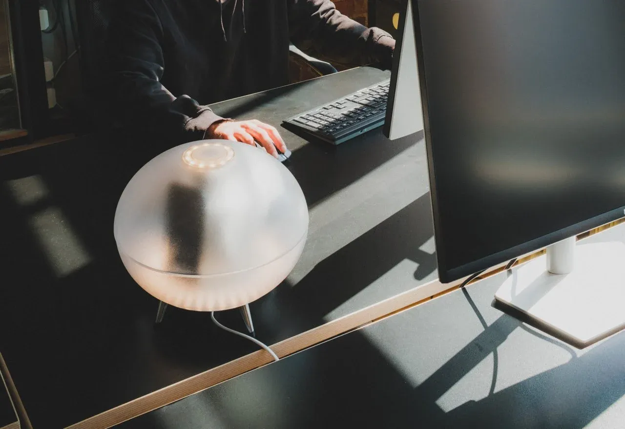 The Oval glowing on a desk beside a keyboard and screen.