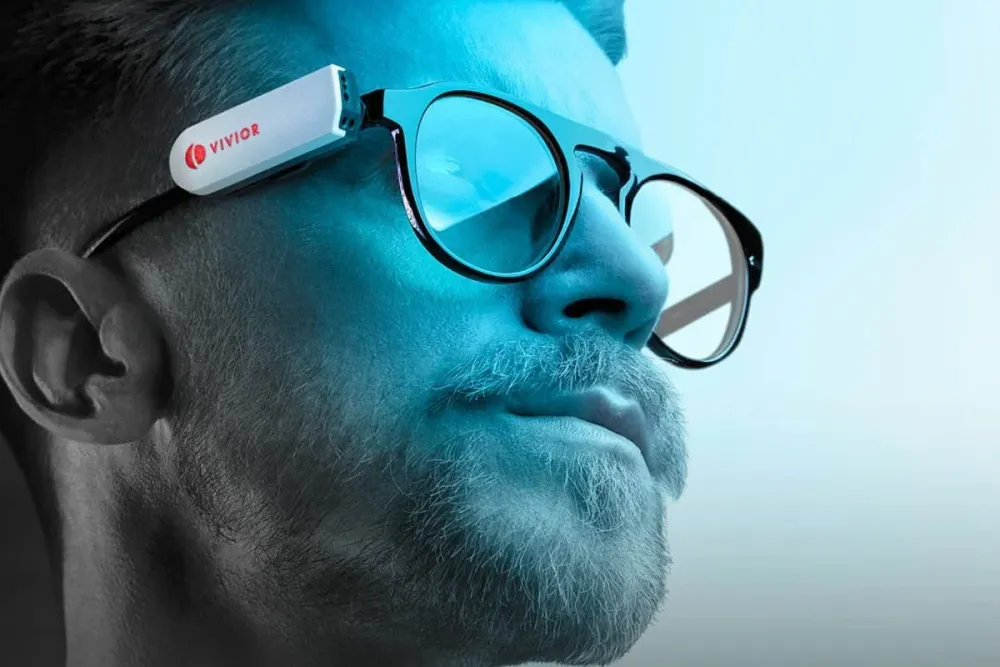A man wearing glasses with the Vivior sensor attached to the temple.