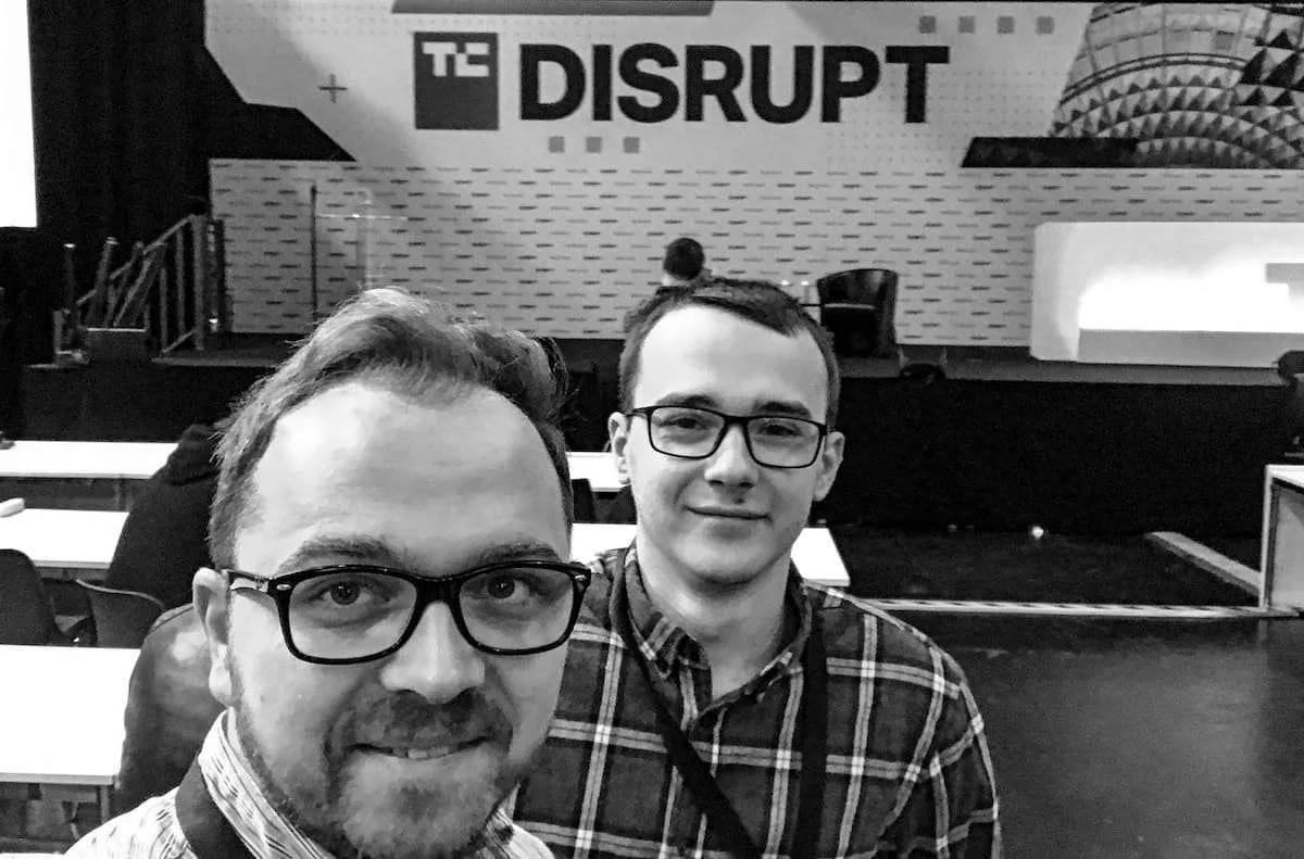 A black-and-white selfie of two Salt &amp; Pepper team members in front of the TechCrunch Disrupt stage.