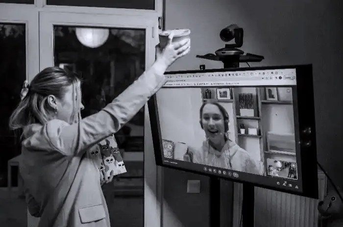 A colleague waving to a teammate on a video call in the office.